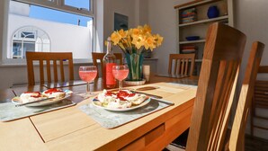 Una mesa de comedor con dos platos de comida, una botella y un jarrón de flores.