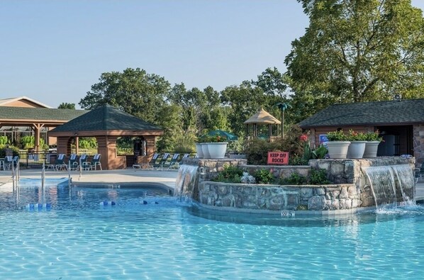 Relax by the serene pool surrounded by lounge chairs and a gazebo, with a nearby rock climbing facility.
