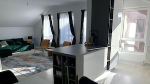 A modern living room with a sofa, a dining table, and a kitchen area. - Spacious 3 Bed Apartment Cluj Floresti Near Vivo (Floresti)