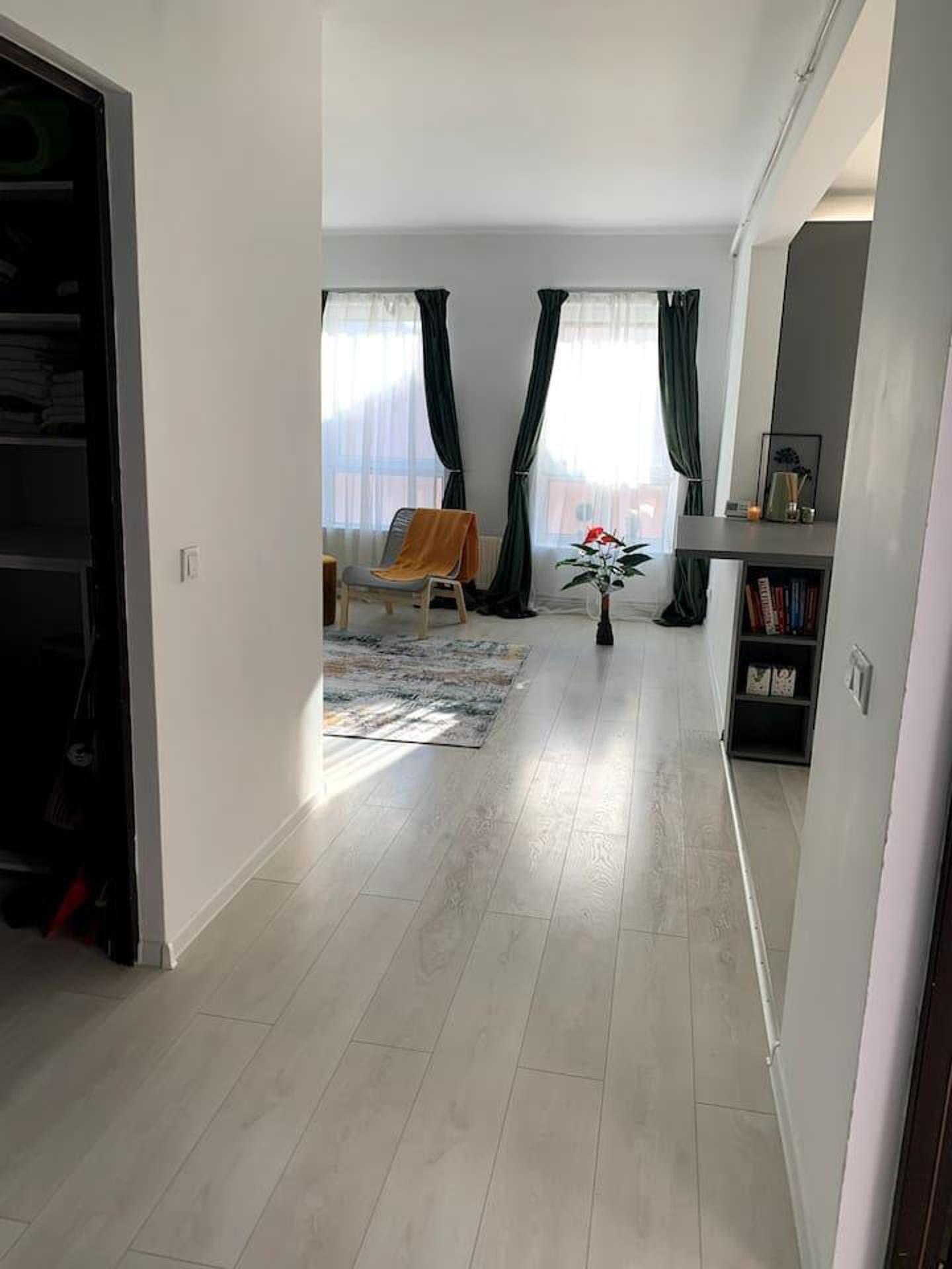 A spacious living area with a sofa, a chair, a small table, and a bookshelf.