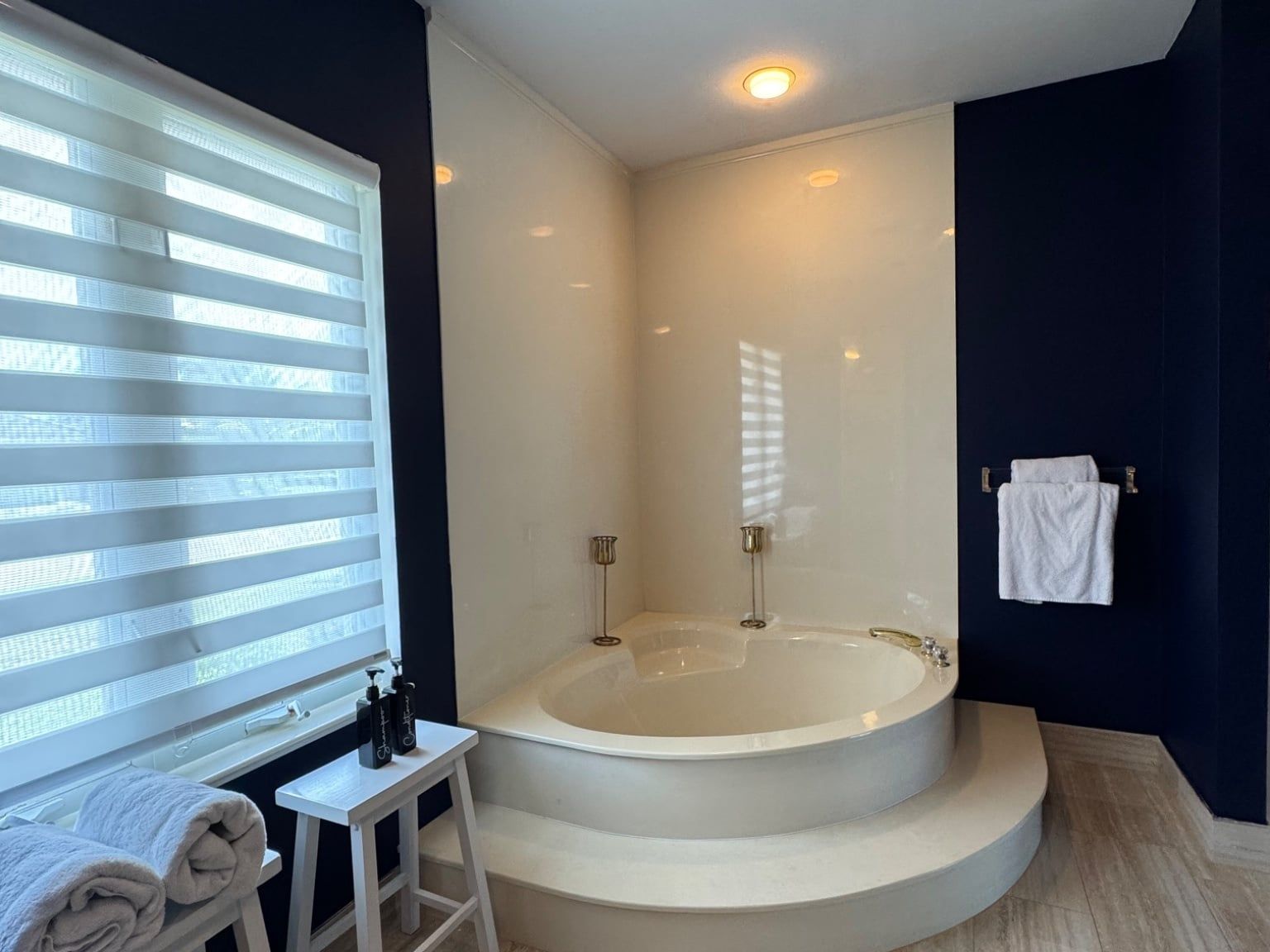 A modern bathroom with a freestanding bathtub, a small table with toiletries, and a towel rack.