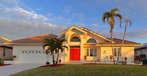 A two-story house with a red door, a garage, and a well-maintained lawn. - Lighthouse 1124 3 Bedroom Home by RedAwning (Marco Island)