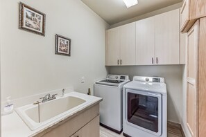 A laundry room with a sink, two washing machines, and cabinets. - Lighthouse 1124 3 Bedroom Home by RedAwning (Marco Island)