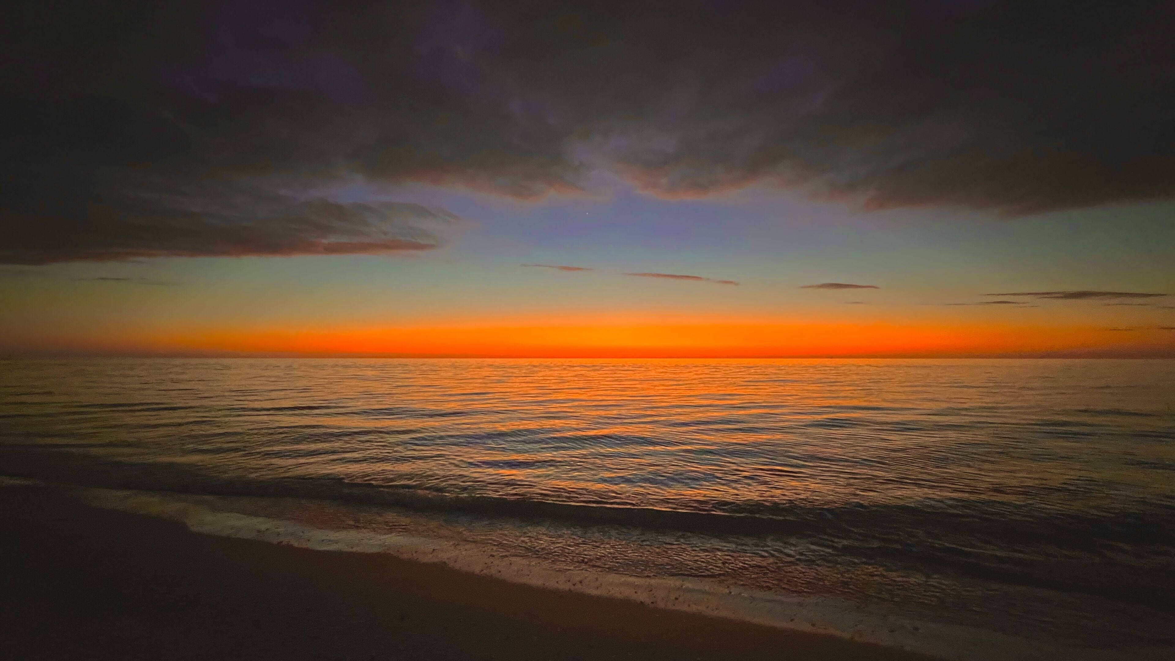 Een strand met golven en een zonsondergang.