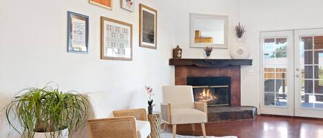 Una sala de estar con chimenea, un tapete blanco y una planta en maceta.