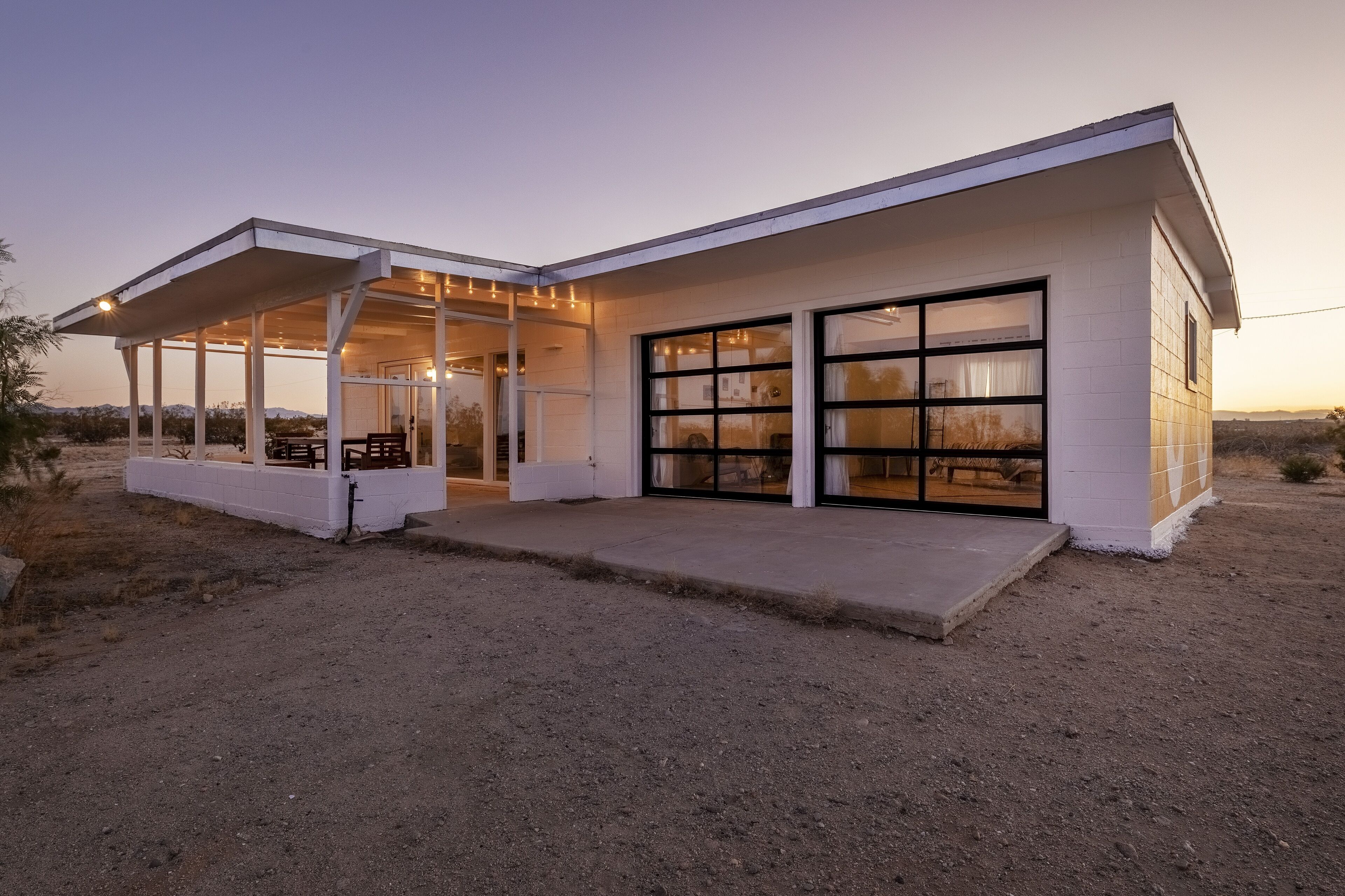 A modern house with a covered patio, large windows, and a garage.