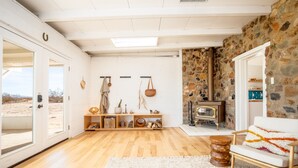 A spacious room with a wooden floor, a white sofa, a stone wall, and a fireplace.