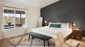 A bedroom with a bed, bedside tables, a bench, a window, and a view of the desert. - Alana House - Pool, Hot Tub, Bbq, Fire Pit + Walk To Hikes! 4 Bedroom Home by RedAwning (Joshua Tree)