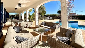 An outdoor patio with wicker furniture, a pool, and a clear view of the surrounding landscape.