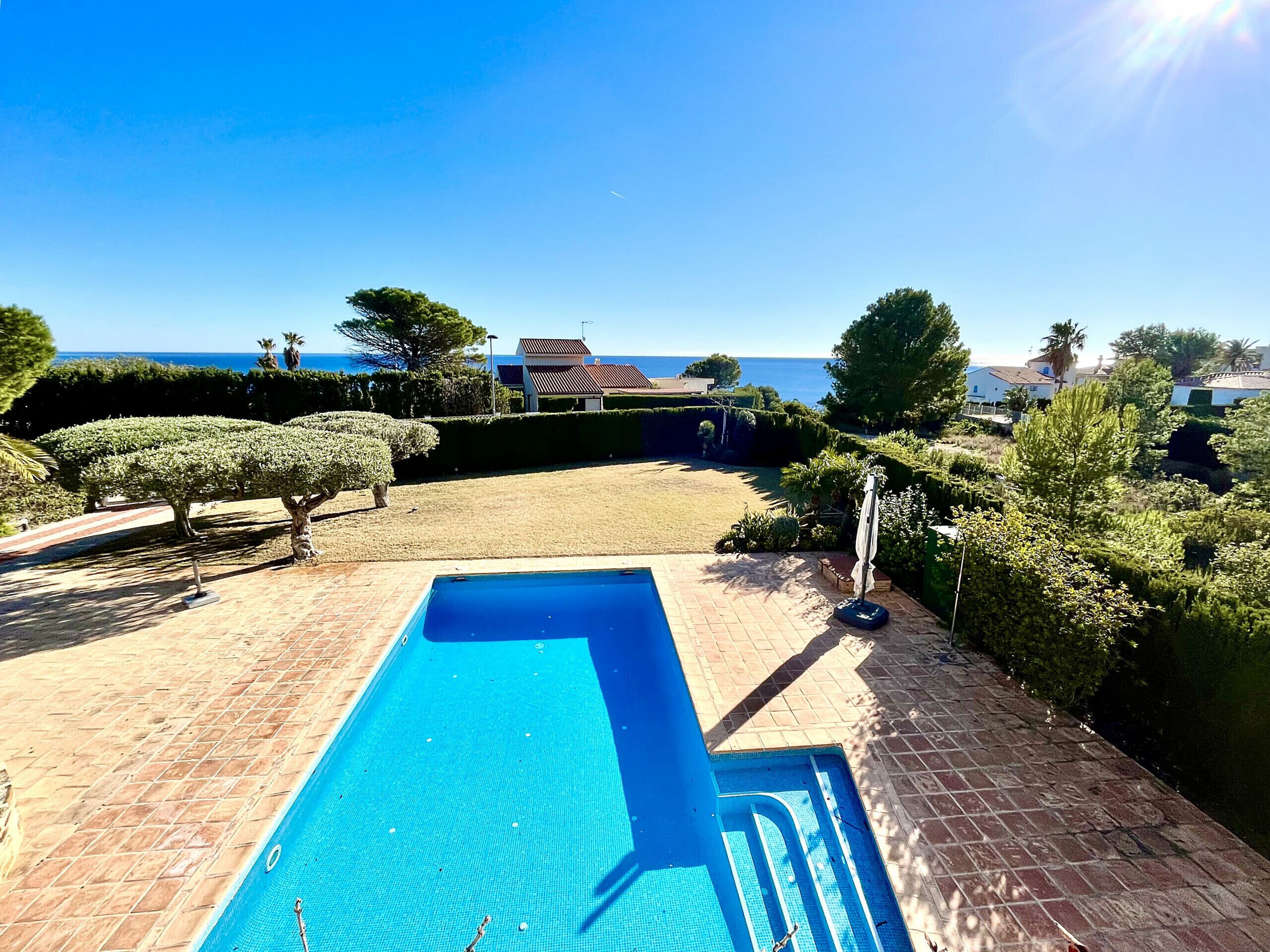 A swimming pool with a clear view of the sea and a grassy area in the background.