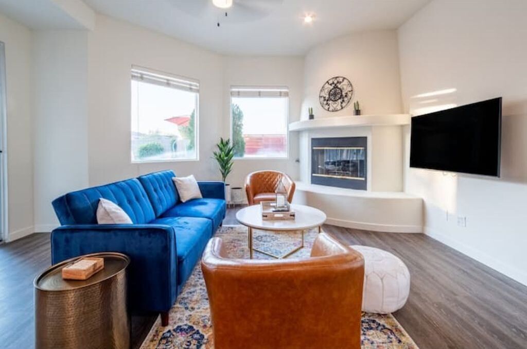 A modern living room with a blue sofa, a round coffee table, and a fireplace.