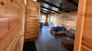 Ein Holzblockbau-Innenraum mit Sofa, Hocker und Essbereich.
