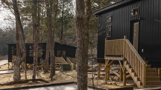 Ein rustikales Blockhaus mit einer Holzdiele und einer Treppe, die zu einer Tür führt.