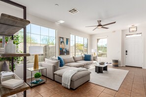 Relax in this stylish living room with a large sofa, coffee table, and side table, offering a comfortable space to unwind with a view of the outdoors.