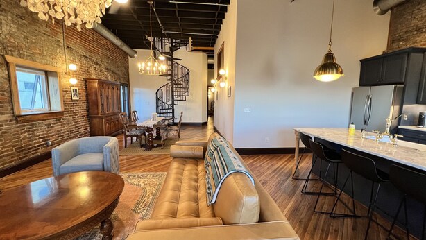 A modern interior with a dining area, a sofa, a kitchen, and a staircase. - 1882 Lofts - 402-Downtown 2nd & Church (Nashville)