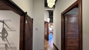 A hallway with wooden doors, a chandelier, and a view into a room with a blue floor. - 1882 Lofts - 402-Downtown 2nd & Church (Nashville)