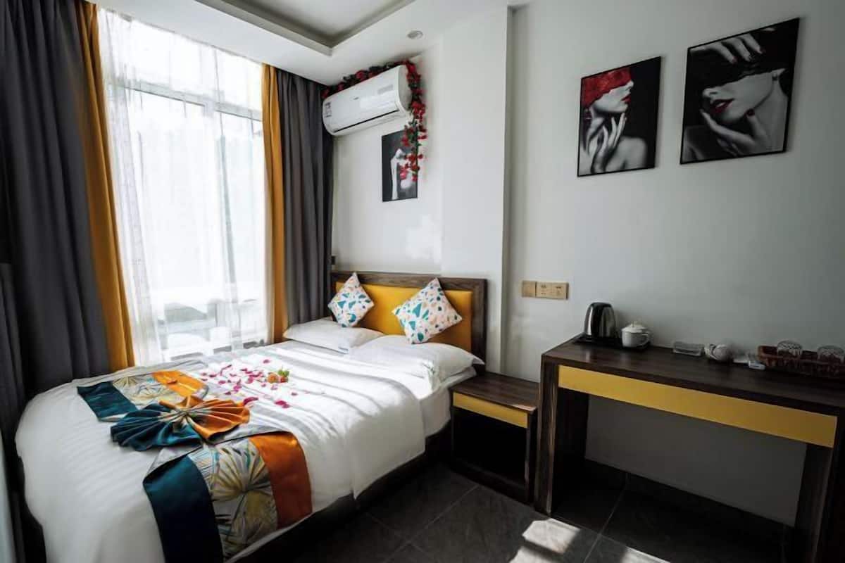 Habitación de hotel con cama, escritorio y ventana con cortinas.
