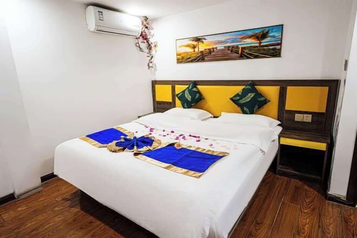 Una cama bien hecha con una colcha azul y dorada, una almohada blanca y un lazo decorativo.