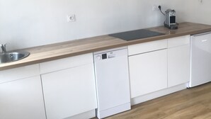 A modern kitchen with white cabinets, a wooden countertop, and a built-in dishwasher. - Renovated house with garage and 300 M2 of land,  (Condé-sur-Sarthe)