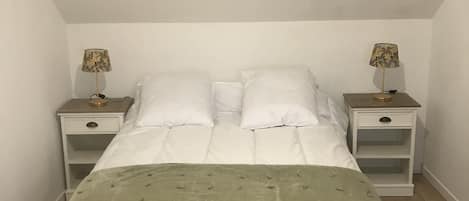 A bedroom with a bed, two bedside tables, and a lamp on each side.
