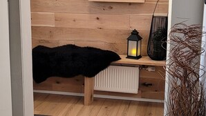 A room with a wooden wall panel, a black fur throw, a small table with a lantern, a radiator, and a fire extinguisher. - A cozy cottage with a sauna in the Golden Circle area. HG-00016818  Id 3221494 (Grímsnes- og Grafningshreppur)