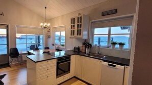 A modern kitchen with a large island, white cabinetry, and a view of a snowy landscape through the windows. - A cozy cottage with a sauna in the Golden Circle area. HG-00016818  Id 3221494 (Grímsnes- og Grafningshreppur)