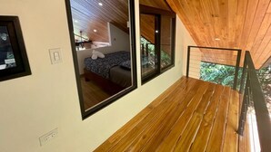Um interior moderno com teto de madeira, grandes janelas e vista para o verde lá fora.
