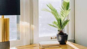 Un tavolo di legno con una lampada nera, una pianta in vaso e una sedia in una stanza con una finestra.