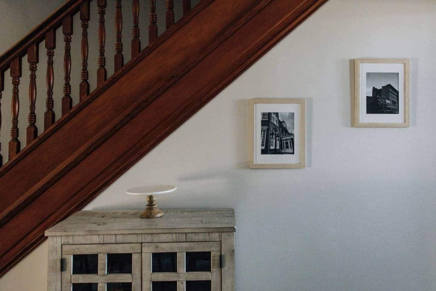 A wooden staircase with a white wall and two framed black-and-white photographs.
