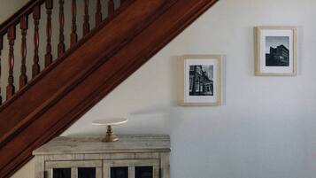 A wooden staircase with a white wall and two framed black-and-white photographs.