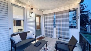 Eine überdachte Veranda mit einer Couch, Stühlen und einem Tisch.