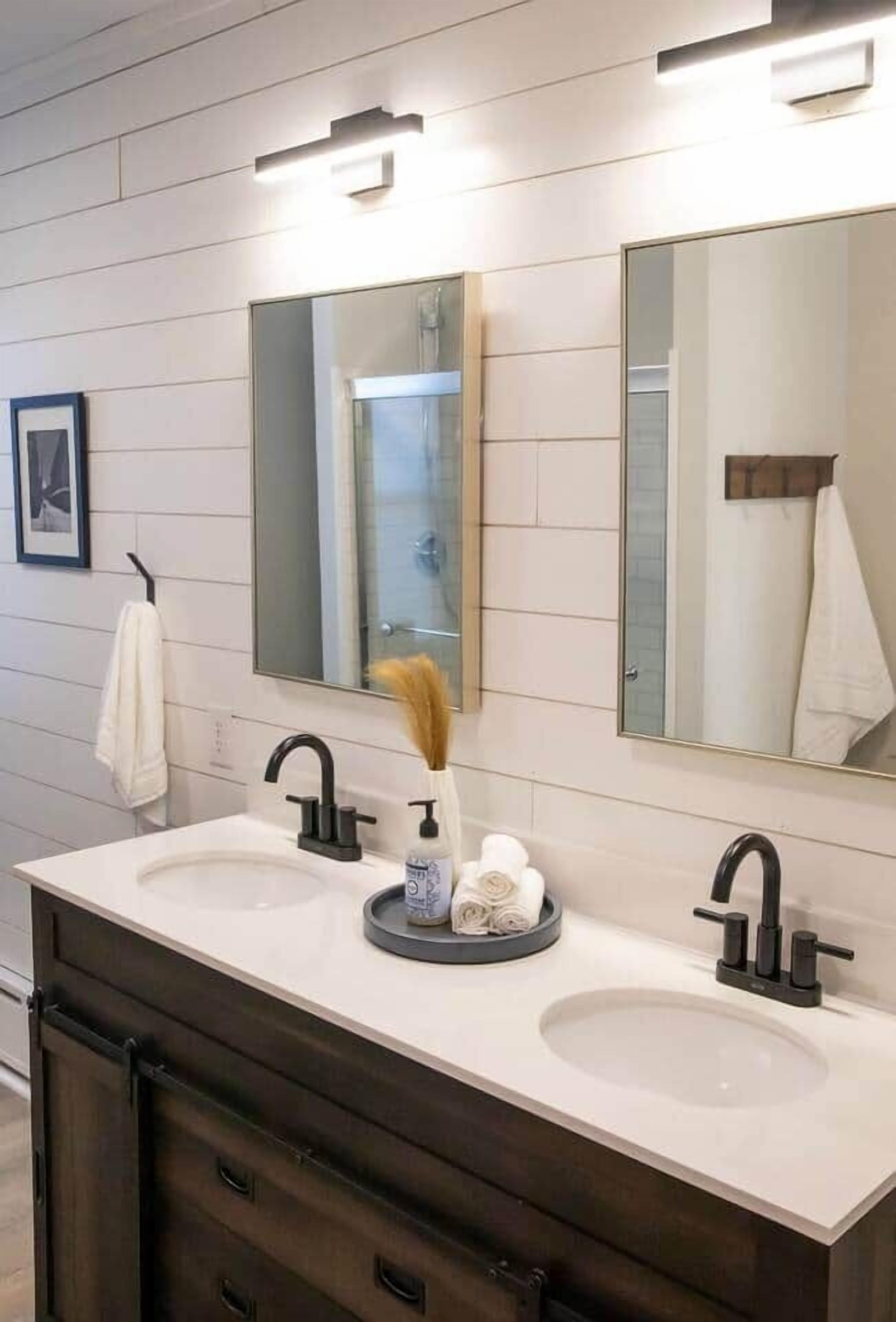 A modern bathroom with two sinks, dark cabinetry, and a large mirror.