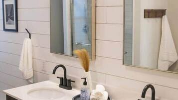 A modern bathroom with two sinks, dark cabinetry, and a large mirror.