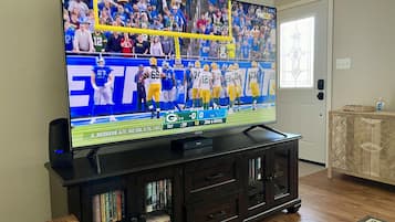 A television displaying a football game, a wooden cabinet with books, and a door with a decorative glass panel.