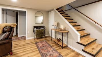 A staircase with wooden steps and black handrails, a brown leather chair, a patterned rug, a small table with candles, and a mirror on the wall.