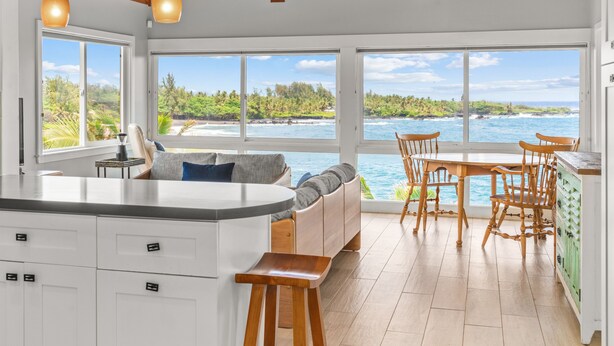 Una cocina con una isla grande, sillas de madera y vistas al océano.