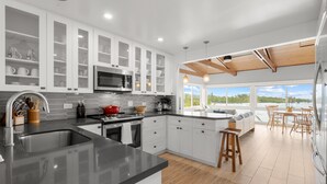 Una cocina moderna con armarios blancos, encimera de granito y vistas al exterior.