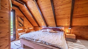A cozy wooden cabin bedroom with a bed, bedside tables, and a window.