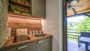 A modern kitchen with wooden countertops, a stainless steel sink, and a view of a balcony with a table and chairs.