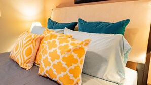 A bed with a beige headboard, covered with a white sheet and two teal pillows. - Explore Bellingham, minutes Airport WWU & Downtown (Bellingham)