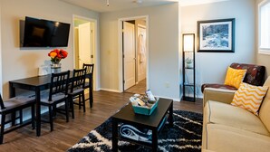 A living room with a TV, dining table, chairs, a coffee table, and a sofa. - Explore Bellingham, minutes Airport WWU & Downtown (Bellingham)