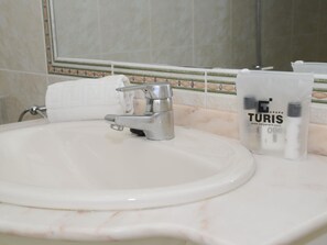 A bathroom sink with a modern faucet, a white towel, and a bag labeled "Grupo Turis One".