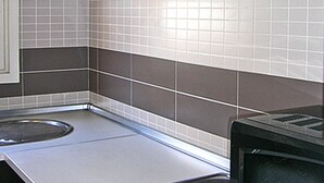 A kitchen with a microwave, stove, and tiled backsplash. - APCOSTAS - Tropik / Two Bedrooms (L'Estartit)