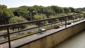 Un balcón con vistas a una carretera, árboles y farolas.