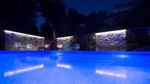 Una piscina al aire libre con muros de piedra y sillas.
