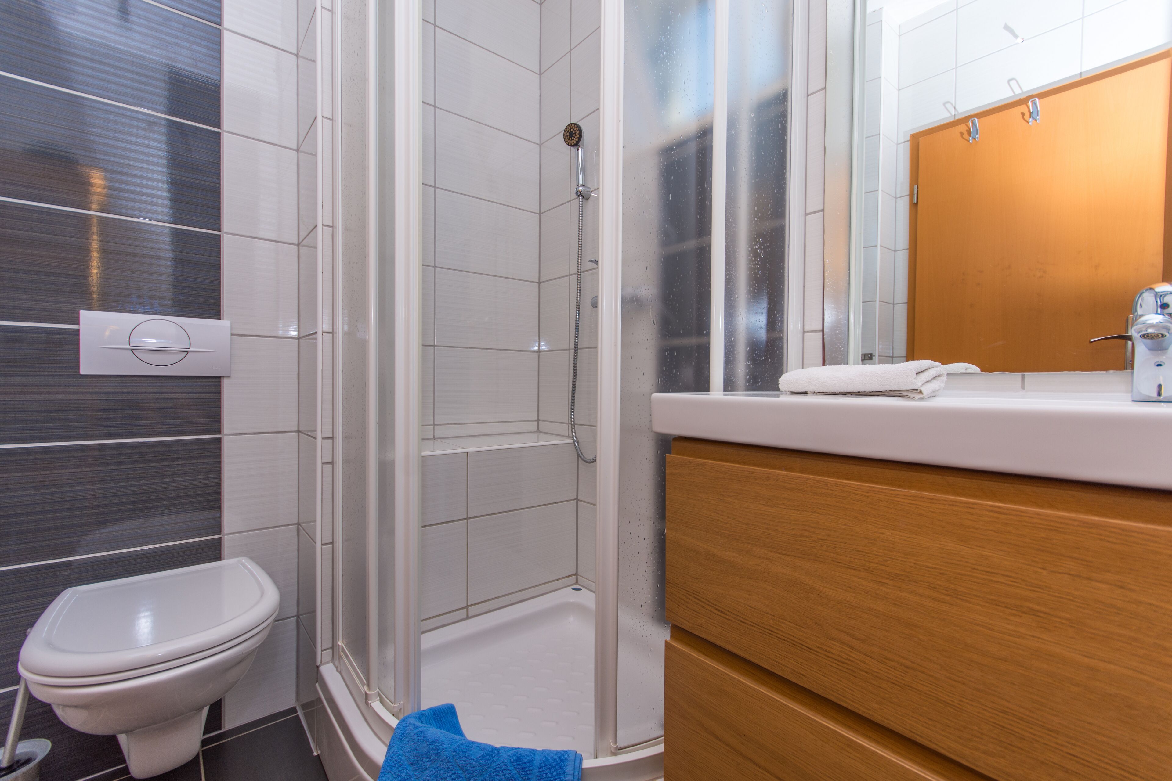 Ein modernes Badezimmer mit Dusche, Toilette und Holzwaschtisch.