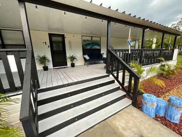 Step up to a serene outdoor retreat with a cozy porch, complete with a bench and lush greenery.