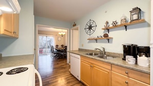 Una cocina moderna con armarios de madera, lavavajillas, pileta doble y espacio para café.