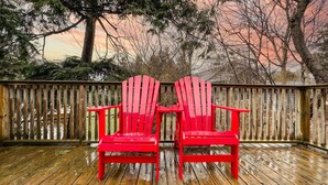 Una terraza de madera con dos sillas Adirondack rojas enfrentadas.