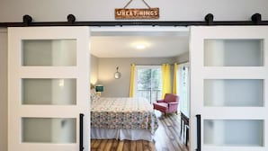 Un dormitorio con una cama, una silla, una ventana y un cartel sobre la puerta.